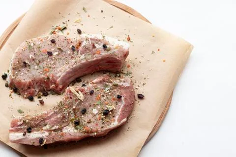 Pink raw pork steaks lie on a wooden board in spices and green dill. Appetizi Stock Photos