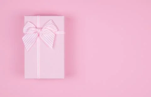 Pink rectangular gift box with pink ribbon on pink background. gift for March Foto stock