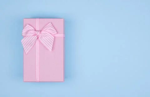 Pink rectangular gift box with pink ribbon on blue background. gift for March Stock Photos