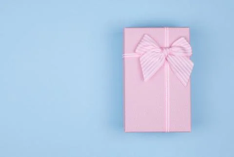 Pink rectangular gift box with pink ribbon on blue background. gift for March 8 Stock Photos