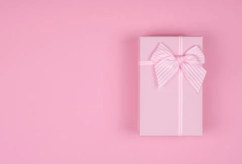 Pink rectangular gift box with pink ribbon on pink background. gift for March Stock Photos