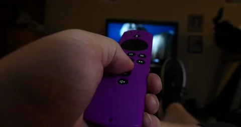 Pink remote control flipping through TV channels blurry background Stock Footage 205492429