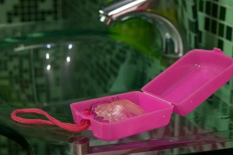 Pink removable braces in the case over the bathroom sink Stock Photos