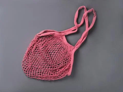 A pink reusable string bag for different products on the grey background. Stock Photos