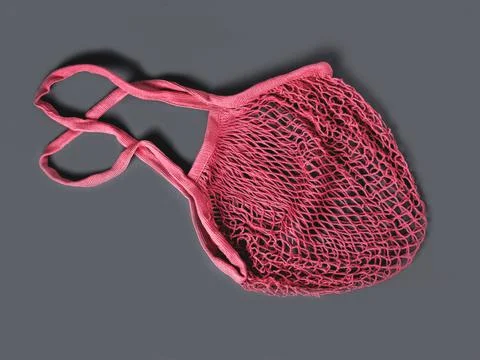 The pink reusable string bag for different products on the gray background. Stock Photos