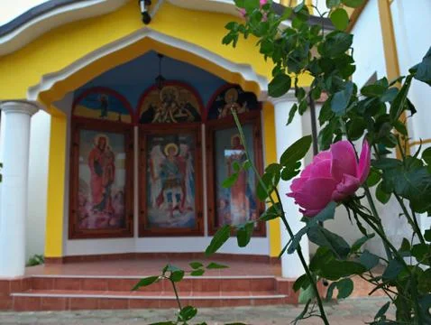 Pink rose in front of small open chapel in monastery Stock Photos