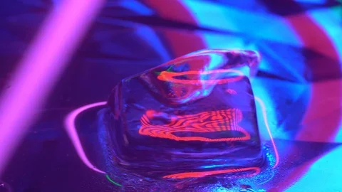 Pink rose melted cube of ice rotating in water with neon lighing Stock Footage 106828577