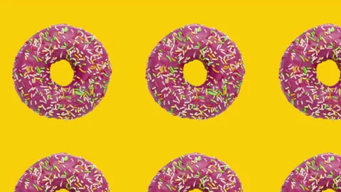 Pink rotating donuts in geometric pattern on a yellow background Stock Footage 149444442