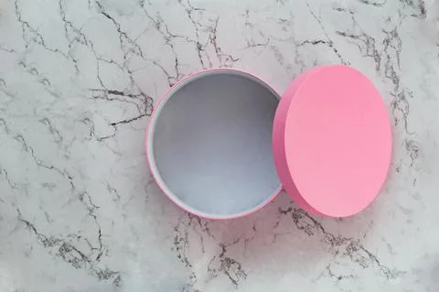 Pink round gift box with open lid on marble background. Round gift box on marble Stock Photos