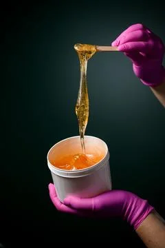 Pink rubber gloves with sugar paste or wax honey in a white plastic container Stock-Fotos