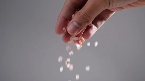 Pink salt falling from hand in slow motion Stock Footage 140666107