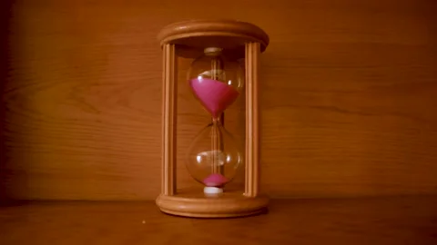 Pink sand running through inside wooden decorative hourglass Stock Footage 150619639