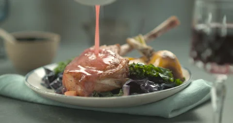 Pink sauce poured on rack of lamb in faience plate with salad and yellow turnip, Stock Footage 199457481