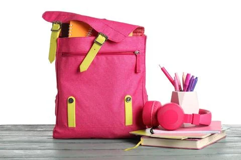 Pink school backpack with different stationery supplies and headphones on woo Stock Photos