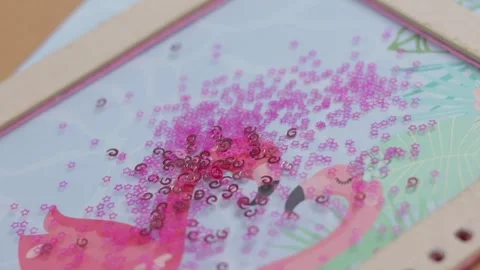 Pink sequins falling on top of hand made notebook, close up Stock Footage 285541097