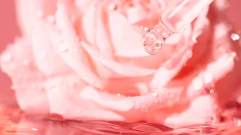 Pink serum fluid, oil drop from dropper falling in water on blurred rose flower Vídeo Stock 199188034
