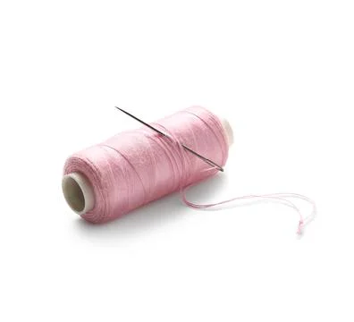 Pink sewing thread spool with needle isolated on white background, closeup Stock Photos