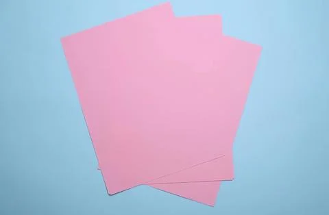 Pink sheets of paper on blue background for crafts or office Stock Photos