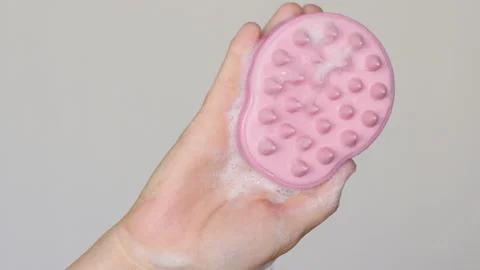 Pink silicone brush with shampoo foam in woman 動画素材 196229727