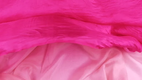 A pink silk fabric falls smoothly onto a magenta textile in slow motion. Stock Footage 337405490