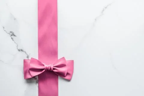 Pink silk ribbon and bow on marble background, girl baby shower present and g Stock Photos