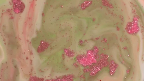 Pink Sparkles Float on Green Liquid 库存影片 123735250