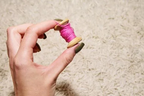 Pink spool of thread in the woman's left hand Stock Photos