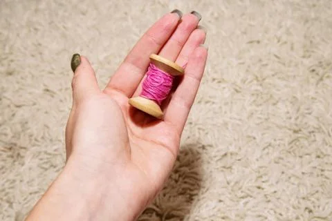 Pink spool of thread in the woman's left hand Stock Photos