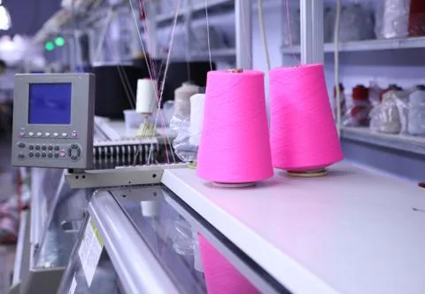 Pink spools of thread on the background of the sewing workshop. Clothing Foto stock