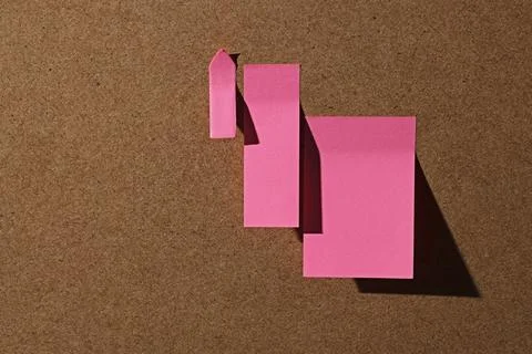Pink square office sticky notes on cork board with hard shadow Stock Photos