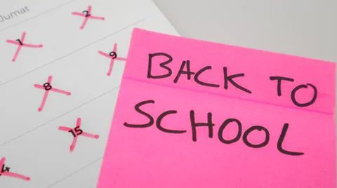 A pink sticky note with "BACK TO SCHOOL" written in bold letters is placed .. Stock Photos
