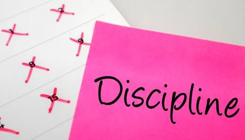 Pink sticky note with Discipline text on a calendar with red marked dates. .. Photos