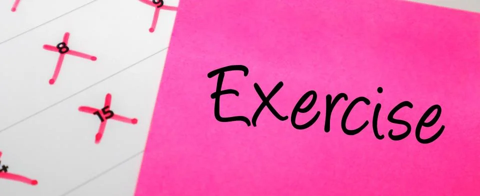 Pink sticky note with Exercise text on a calendar with red marked dates. Co.. Stock Photos