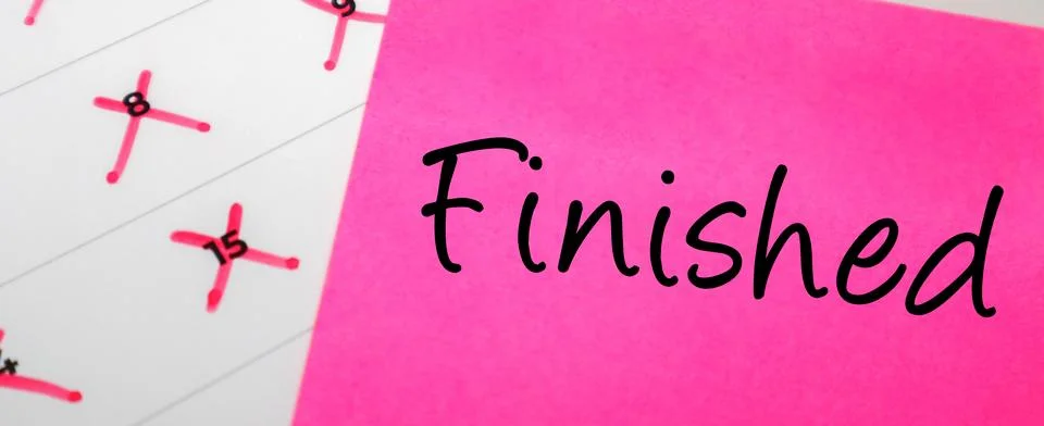 Pink sticky note with Finished text on a calendar with red marked dates. Co.. Stock Photos