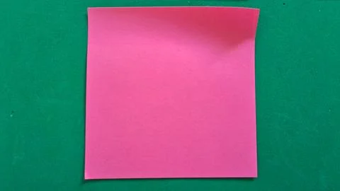 Pink sticky note on green background. Blank adhesive paper for office reminders Stock Photos