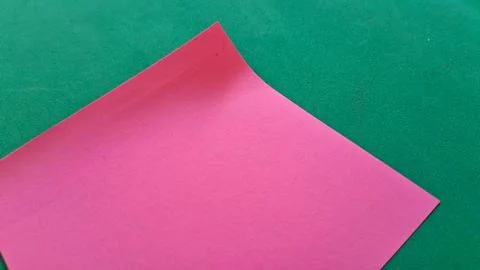 Pink sticky note on green background. Blank adhesive paper for office reminders Stock Photos