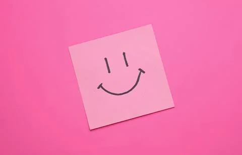 Pink sticky note with a happy smiley face on pink background Stock Photos