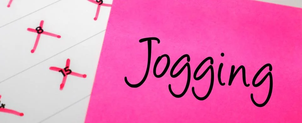 Pink sticky note with Jogging text on a calendar with red marked dates. Con.. Stock Photos