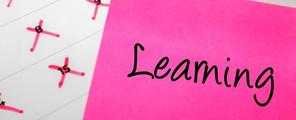 Pink sticky note with Learning text on a calendar with red marked dates. Co.. Stock Photos