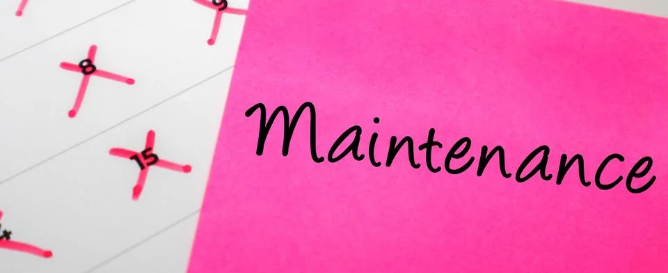 Pink sticky note with Maintenance text on a calendar with red marked dates... Stock Photos