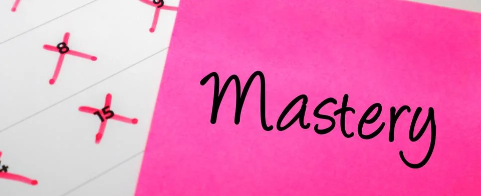 Pink sticky note with Mastery text on a calendar with red marked dates. Con.. Stock Photos