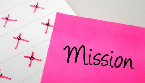 Pink sticky note with Mission text on a calendar with red marked dates. Con.. Stock Photos