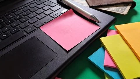 Pink sticky note placed on a black laptop keyboard surface Stock Photos