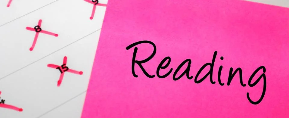 Pink sticky note with Reading text on a calendar with red marked dates. Con.. Stock Photos