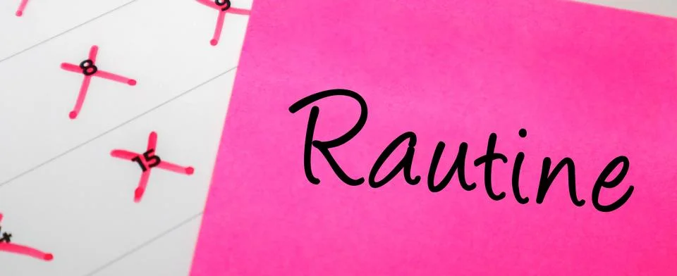 Pink sticky note with Routine text on a calendar with red marked dates. Con.. Stock Photos