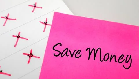Pink sticky note with Save Money text on a calendar with red marked dates. .. Stock Photos