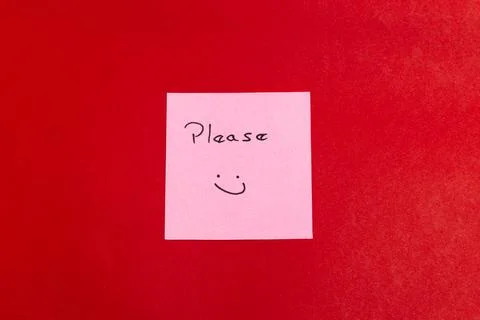 A pink sticky note with a smiley face on it and the word please written on it Stock Photos