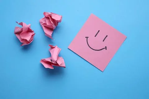 Pink sticky note with smiley face on blue background Stock Photos