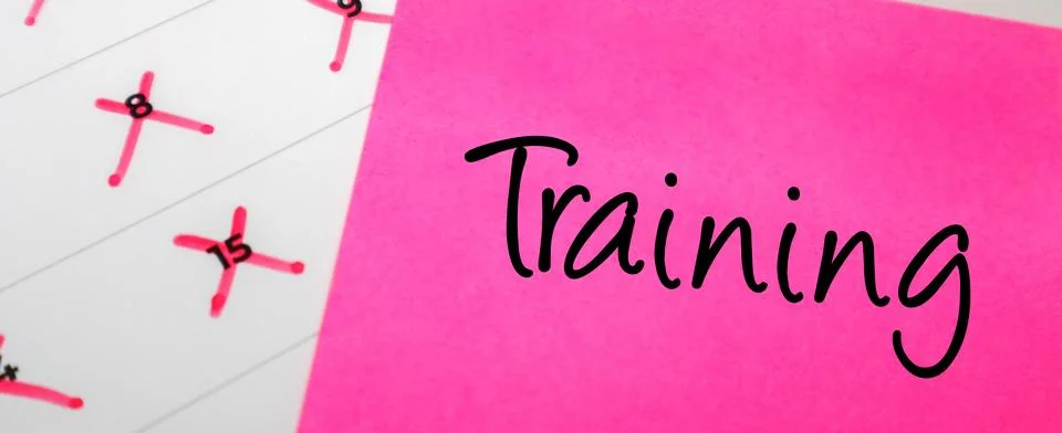 Pink sticky note with Training text on a calendar with red marked dates. Co.. Stock Photos