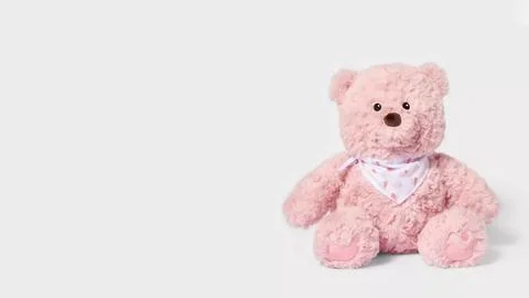 Pink stuffed bear sits on a plain background with a white bandana Fotos de archivo